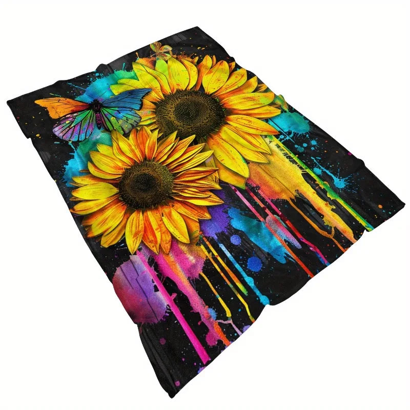 A dark flannel blanket featuring a vibrant watercolor print of sunflowers and butterflies in yellow, orange, blue, and purple