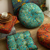 A vibrant teal and green bohemian cotton linen floor cushion with a patterned fabric is shown on a wooden floor.