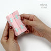 A hand holds a pink infinity magic cube fidget toy with light blue accents for stress relief.