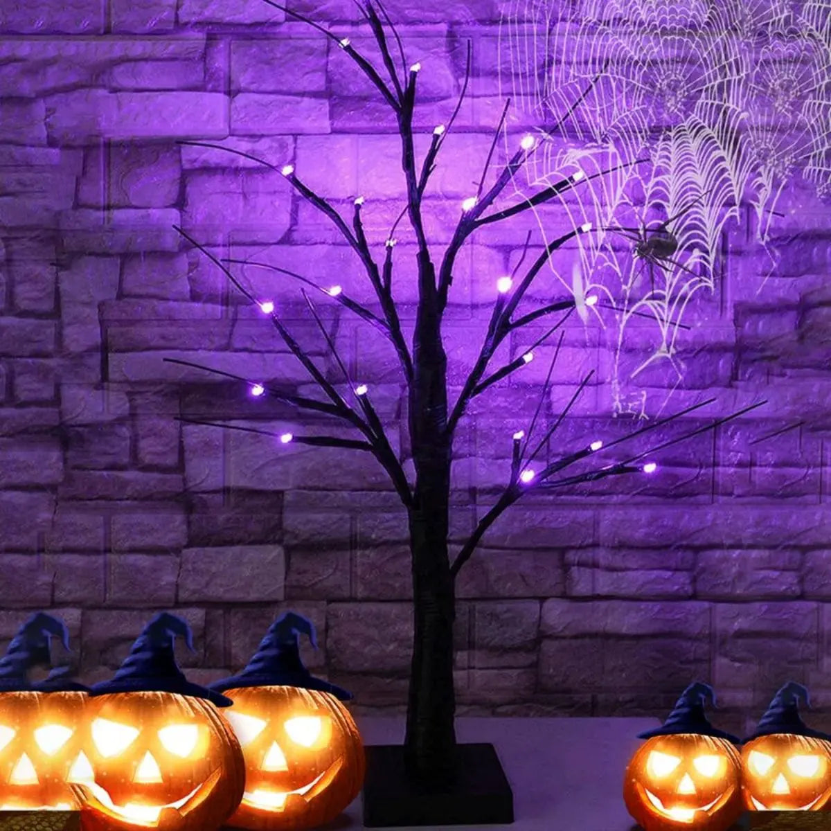 An LED Halloween birch tree with orange and purple lights displayed against a purple brick wall.