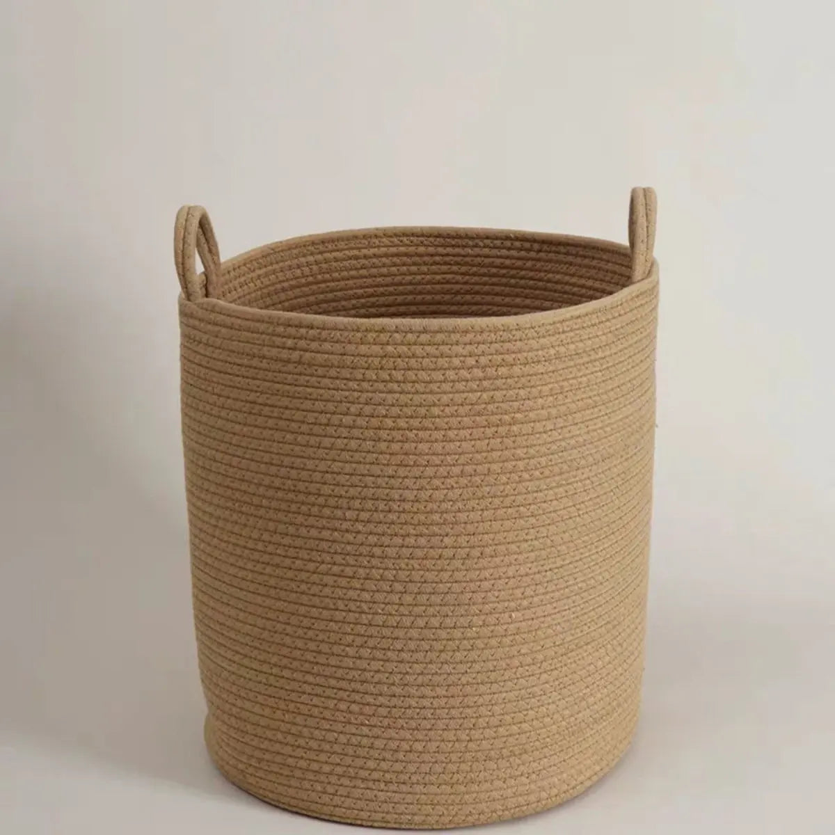 A beige handwoven cotton rope storage basket with handles.