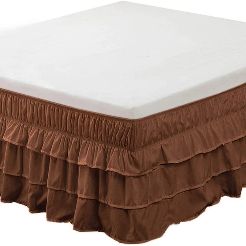 Brown elastic bed skirt with ruffled hem covering the base of a white mattress.