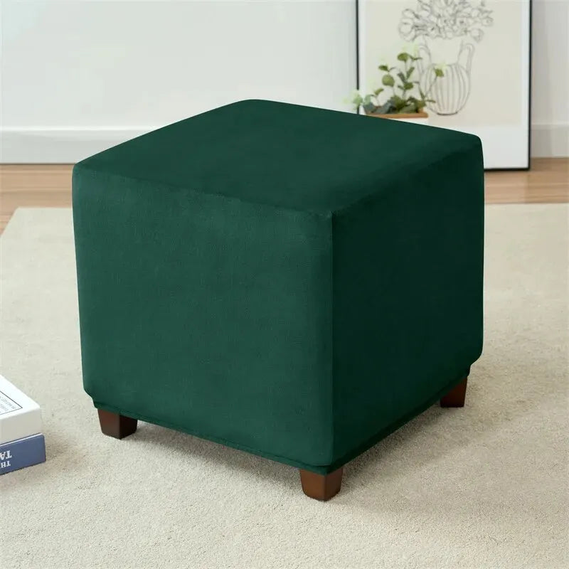 A dark emerald green stretch velvet ottoman slipcover used as a footrest.