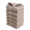 A stack of six beige premium pure cotton face towels folded neatly.