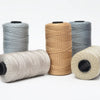 Four spools of beige, gray, and blue 3-ply polyester knitting yarn for crochet and hand crafts
