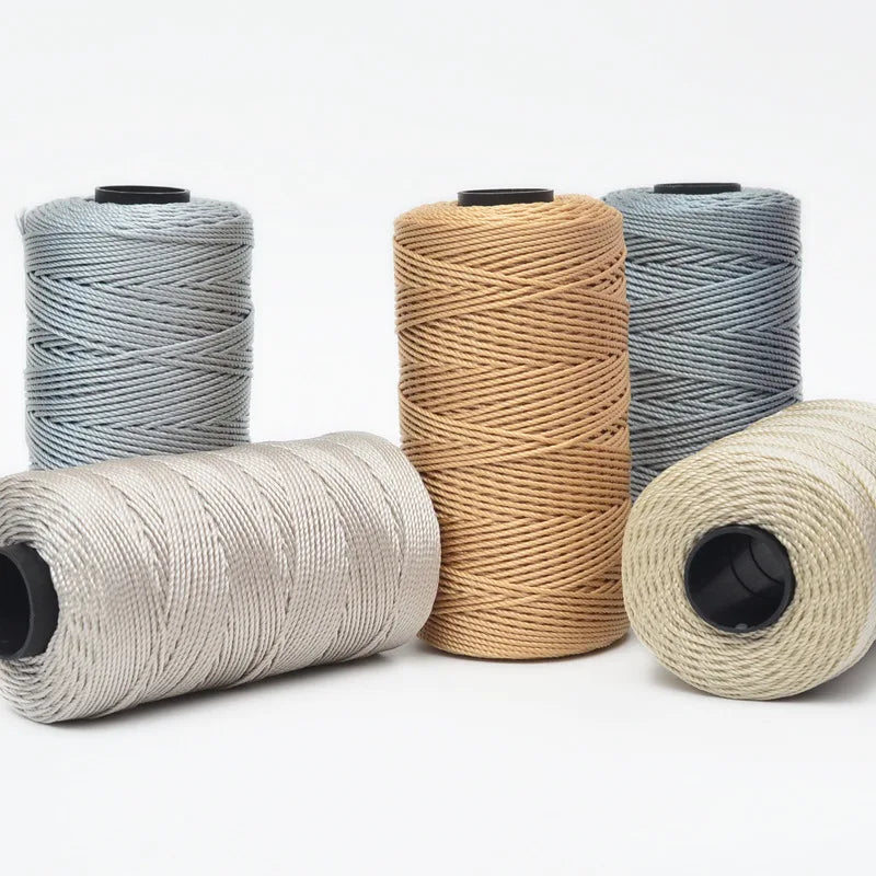 Four spools of beige, gray, and blue 3-ply polyester knitting yarn for crochet and hand crafts