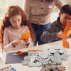 A child is assembling a DIY metal button parts kit with various silver and copper-toned buttons on a white table.