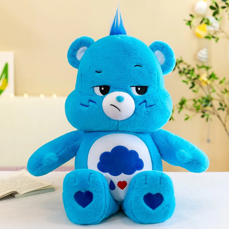 Muñeco de peluche Kawaii Care Bears arcoíris azul con expresión triste sobre una superficie blanca.