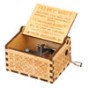 A vintage hand-cranked wooden music box with an open lid featuring engraved text and a small metal crank.