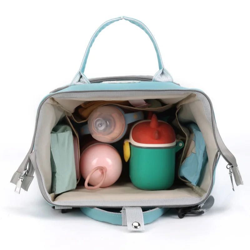 A light blue diaper backpack with a large capacity interior showing various items.