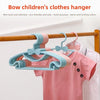 Light blue and pink plastic hangers with bow designs hanging on a wooden rod.