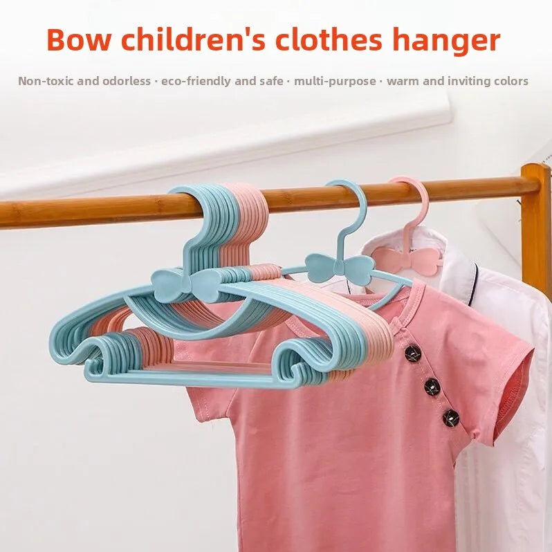 Light blue and pink plastic hangers with bow designs hanging on a wooden rod.