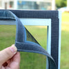 A hand is adjusting a black and gray reusable self-adhesive mosquito window screen frame.