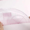 A clear plastic sewing ruler set with a flexible French curve design and a grid for measuring fabric.