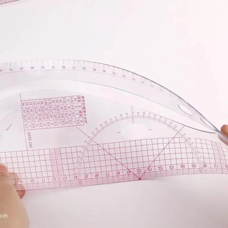 A clear plastic sewing ruler set with a flexible French curve design and a grid for measuring fabric.
