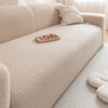 A light beige plush sofa with a matching throw pillow and a small tray of fruit on the seat.