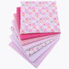 A bundle of pink and white floral dot patterned cotton fabric squares for patchwork and quilting.