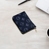 A dark blue compact zippered card holder wallet resting on a light wooden surface next to a pen and a laptop.