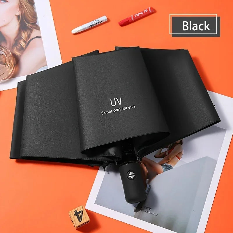 Black automatic compact umbrella shown open on an orange background with a red pen and a UV label nearby.