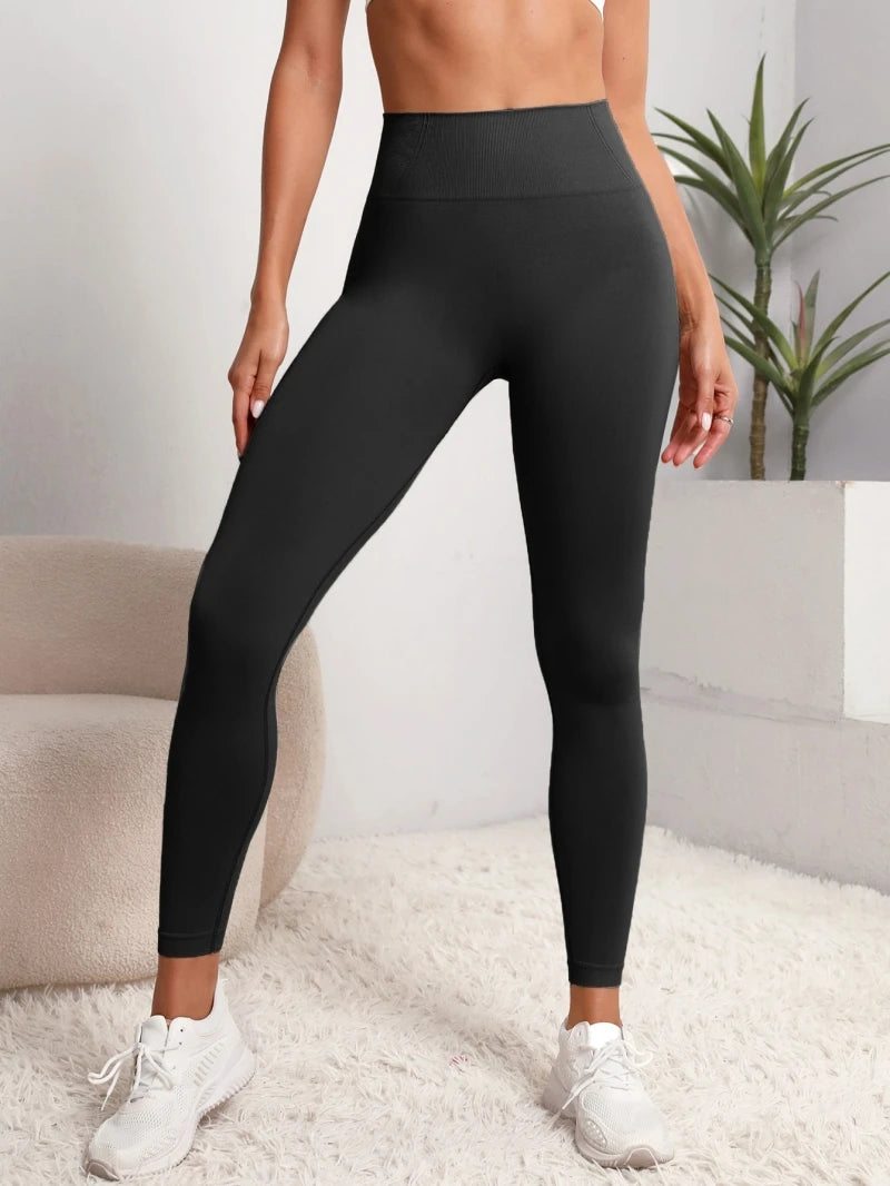 A model wearing black high-waist sculpting leggings and white sneakers.