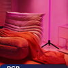 A pink room features an orange fabric draped over a sofa, illuminated by a vertical purple LED light.