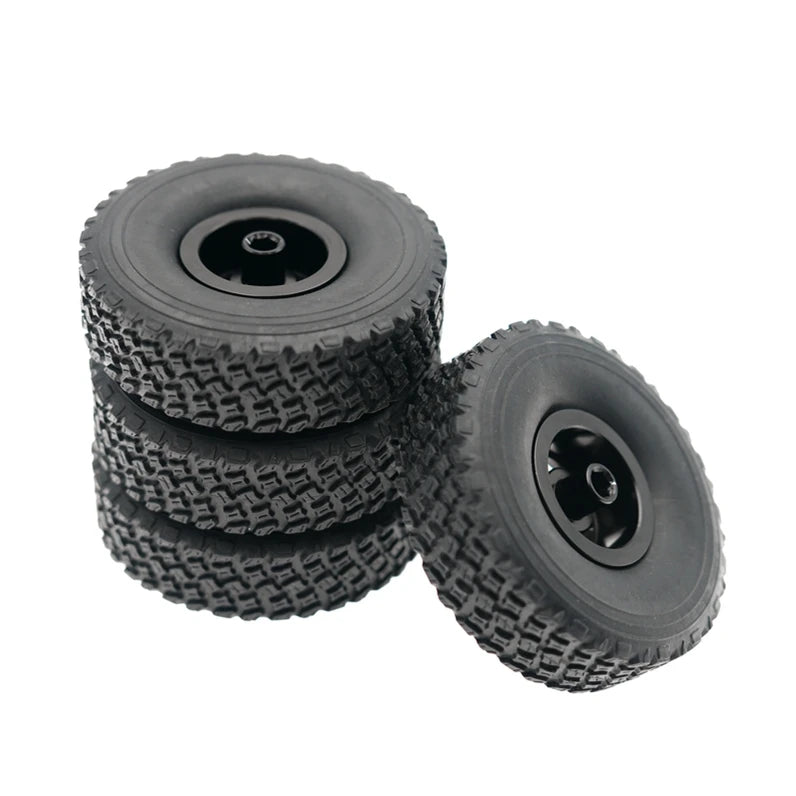 A stack of four black RC car upgrade wheels with metal rims and soft tires.