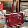 A maroon transparent shoulder bag with white lace trim hanging in a display rack.