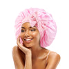 A woman is wearing a pink satin sleeping bonnet with an adjustable tie.