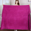 A woman holds up a vibrant magenta microfiber bath towel displaying its texture and drape.