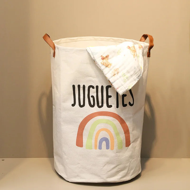 A white fabric storage basket with a rainbow print and leather handles.
