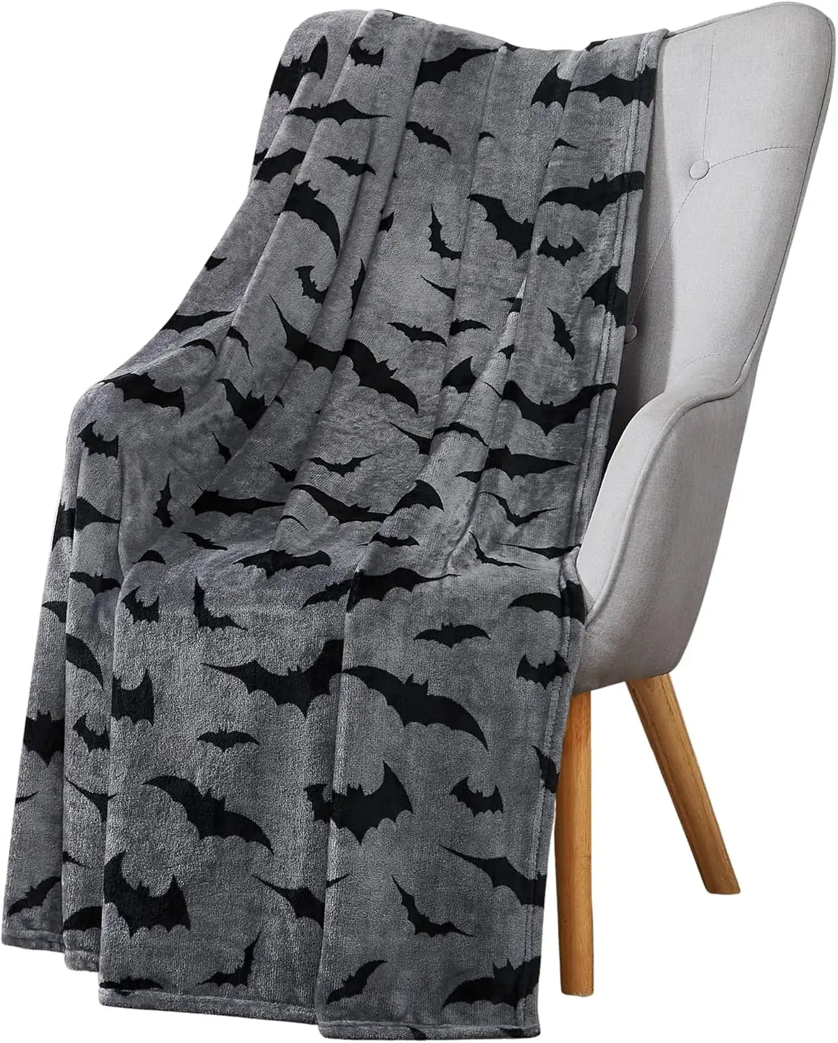 Une couverture gris à flanelle avec un motif de chauve-souris noire drapée sur une chaise gris clair.