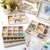 A wooden jewelry organizer tray with multiple compartments holding various silver and gold jewelry pieces.