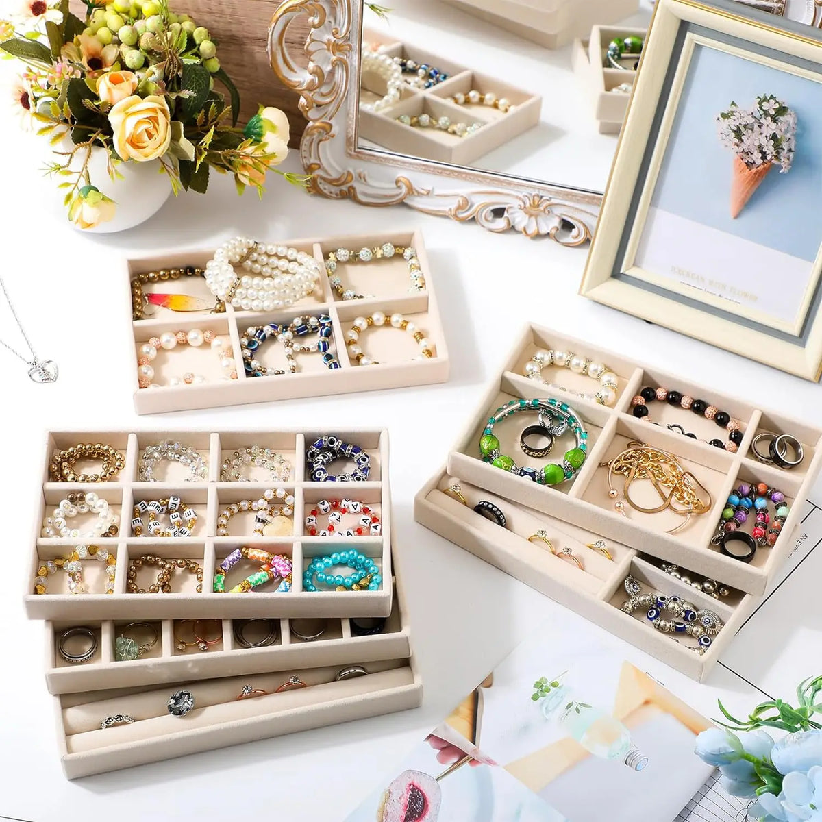A wooden jewelry organizer tray with multiple compartments holding various silver and gold jewelry pieces.