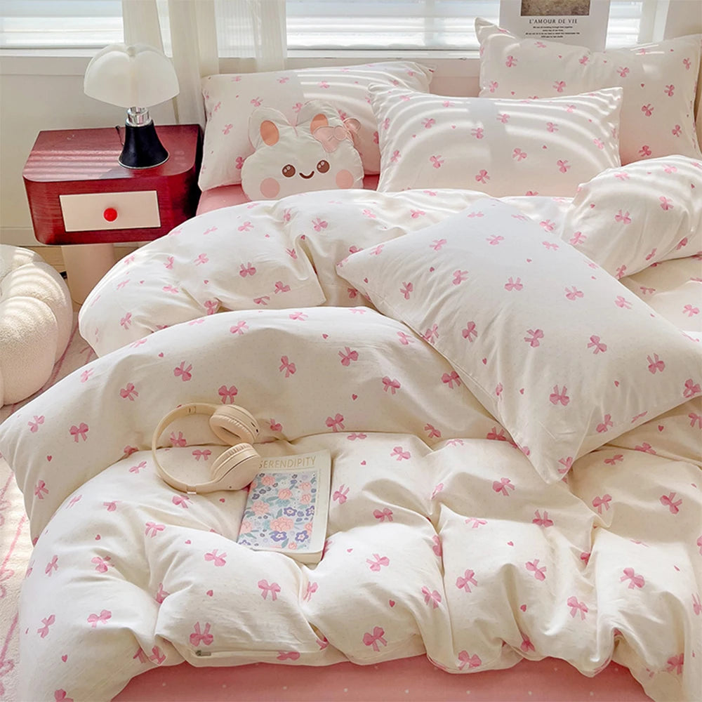 A set of white bedding featuring a pink bow print on a duvet cover and pillows.