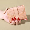 A light pink quilted women's double-zip PU leather wallet with card slots being held in a hand.