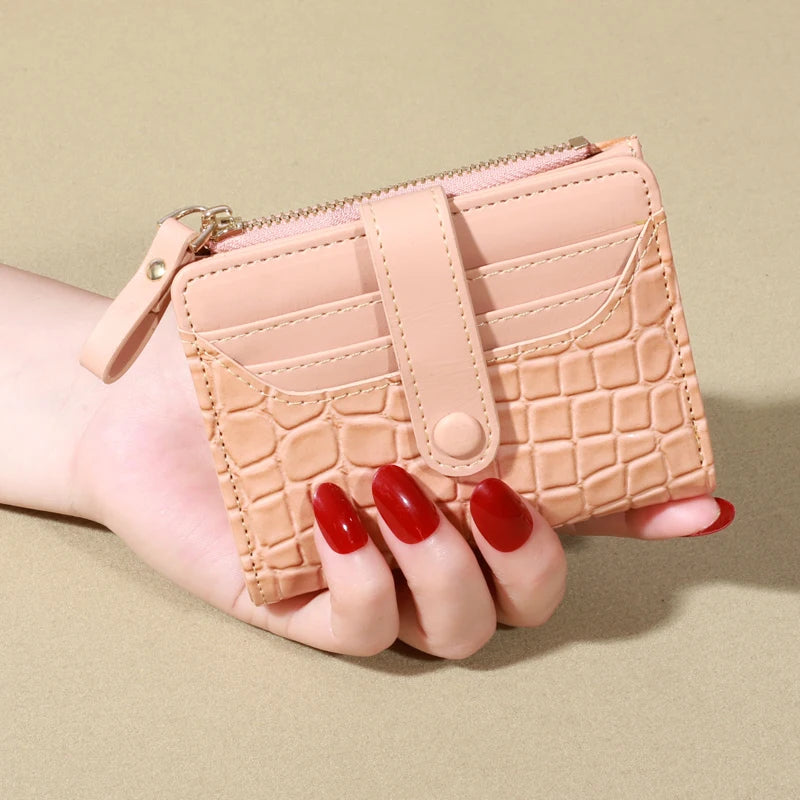 A light pink quilted women's double-zip PU leather wallet with card slots being held in a hand.
