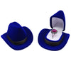 A royal blue velvet cowboy hat is displayed next to an open storage box containing a silver ring.