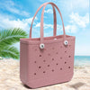 Pinkes, tragbares EVA-Strandtasche mit perforierten Details auf einem Sandstrand in der Nähe des Ozeans.