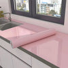 Pearlescent pink marble peel and stick wallpaper rolled out on a kitchen countertop.