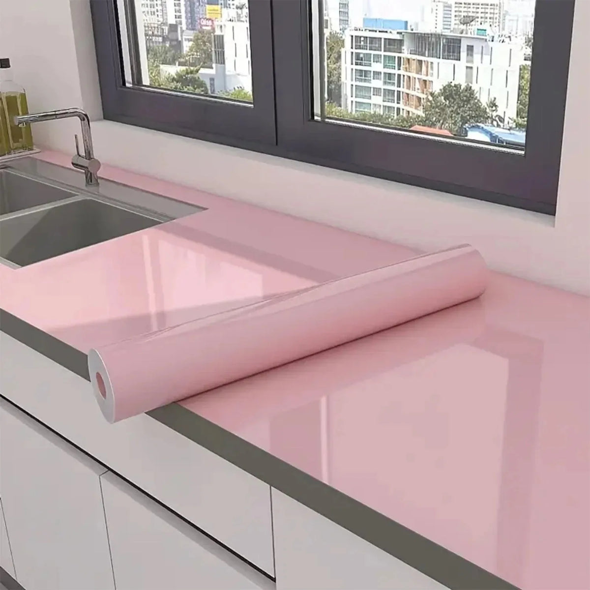 Pearlescent pink marble peel and stick wallpaper rolled out on a kitchen countertop.