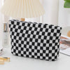 A black and white checkered plaid makeup bag with a zipper resting on a white surface.