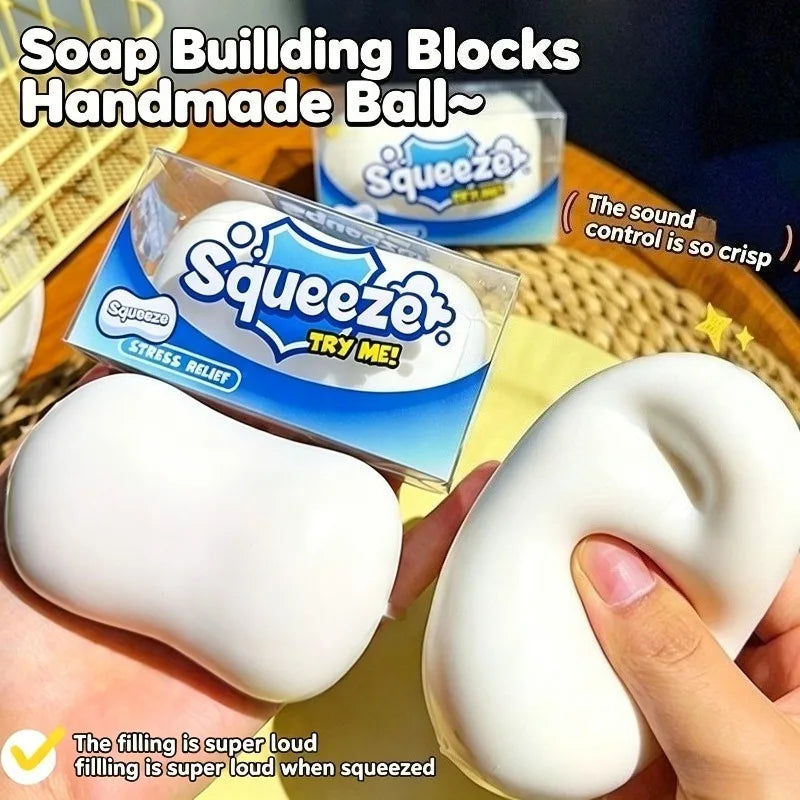 A hand squeezes a white squishy stress relief ball inside its packaging.