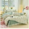 Helles grün-lavendelfarbenes Blumen-Duvetcover auf einem Bett mit durchscheinenden weißen Vorhängen und natürlichem Licht.