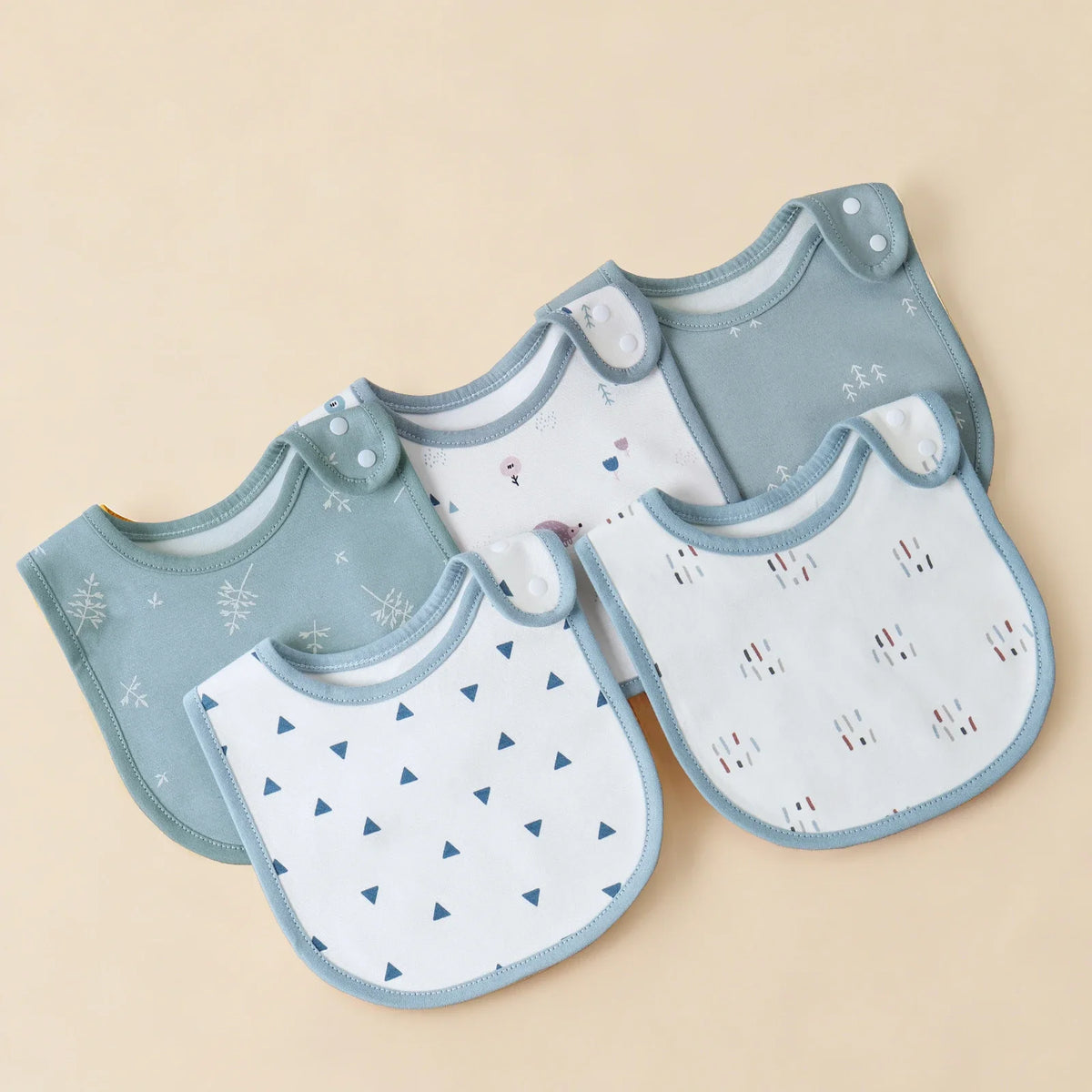 A set of light blue and white cotton baby bibs with U-shaped designs displayed on a neutral background.