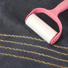 A pink plastic towel ring holds a roll of gold-striped towel fabric on a dark gray towel.