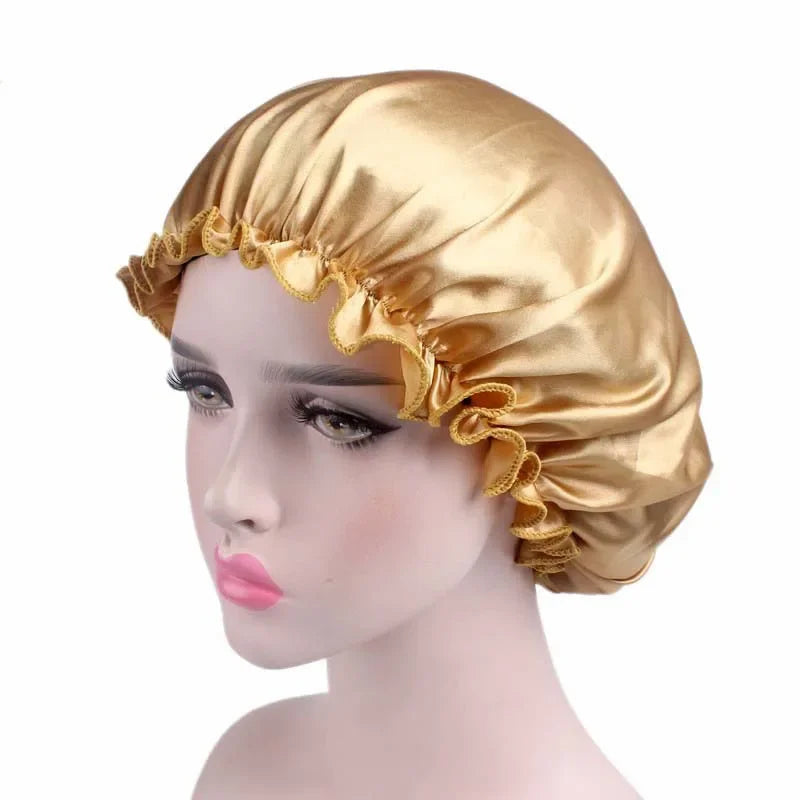 A golden satin hair bonnet with ruffled edges displayed on a mannequin head.