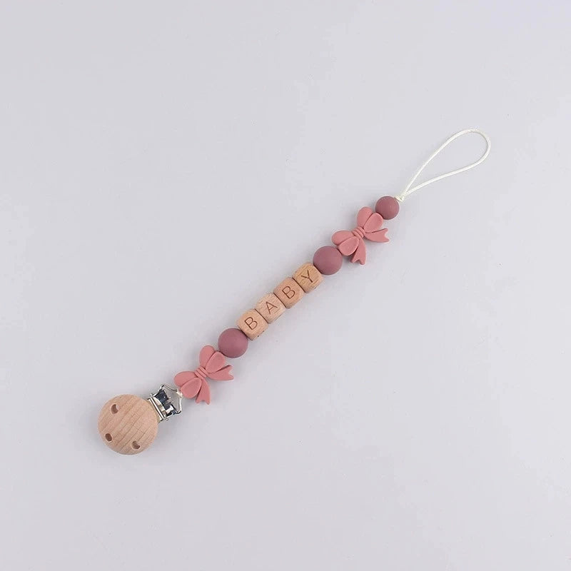 A beaded silicone pacifier clip with a wooden baby teething lanyard and pink floral accents.
