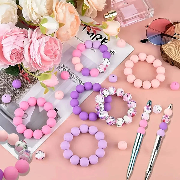 A collection of soft silicone floral beads in various shades of pink and purple arranged for jewelry making.