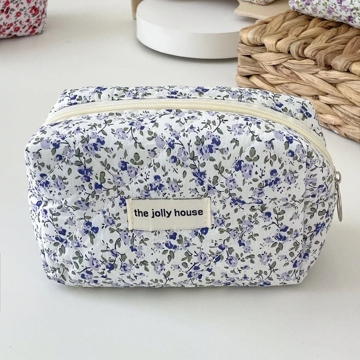 A quilted floral makeup bag with a white background and blue and purple flowers, featuring a zipper closure.