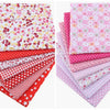 A bundle of pink, red, and white cotton fabric squares featuring floral dot patterns for patchwork and quilting.
